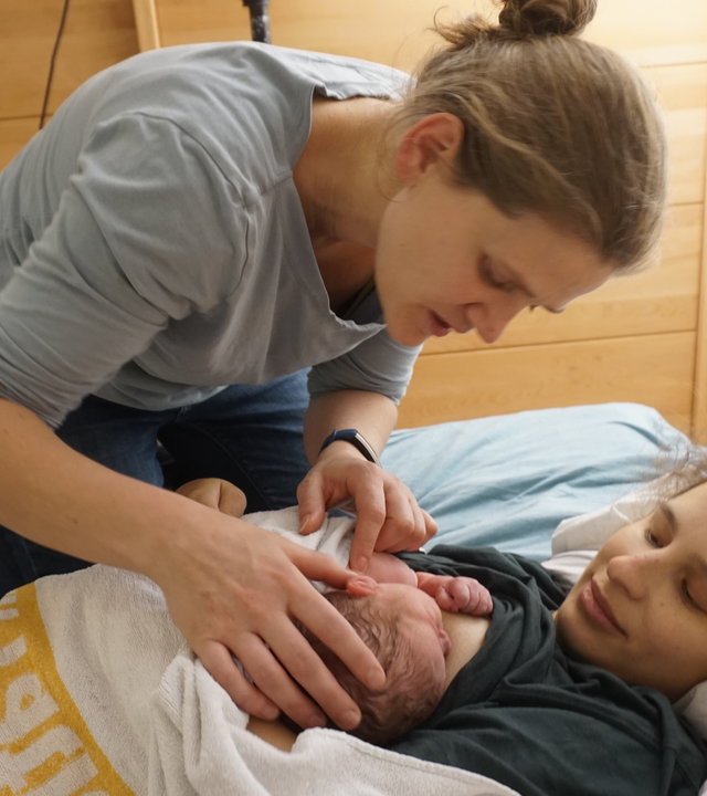 "37°: Keine leichte Geburt - Hebammen am Limit": Die junge Mutter liegt mit ihrem Säugling im Bett. Hebamme Anna kümmert sich um Mutter und Kind.