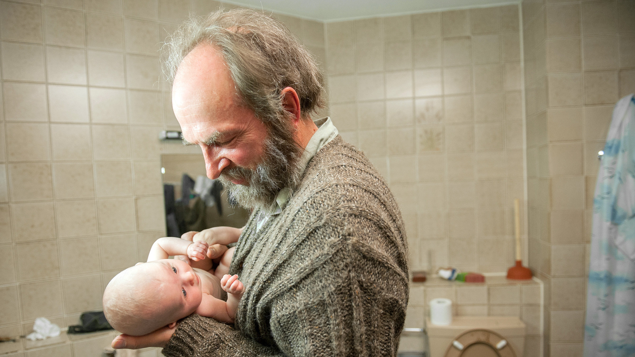 "Glückskind": Hans Scholz (Herbert Knaup) steht in seinem Bad und hält ein Baby in seinen Armen. Er schaut es liebevoll an.