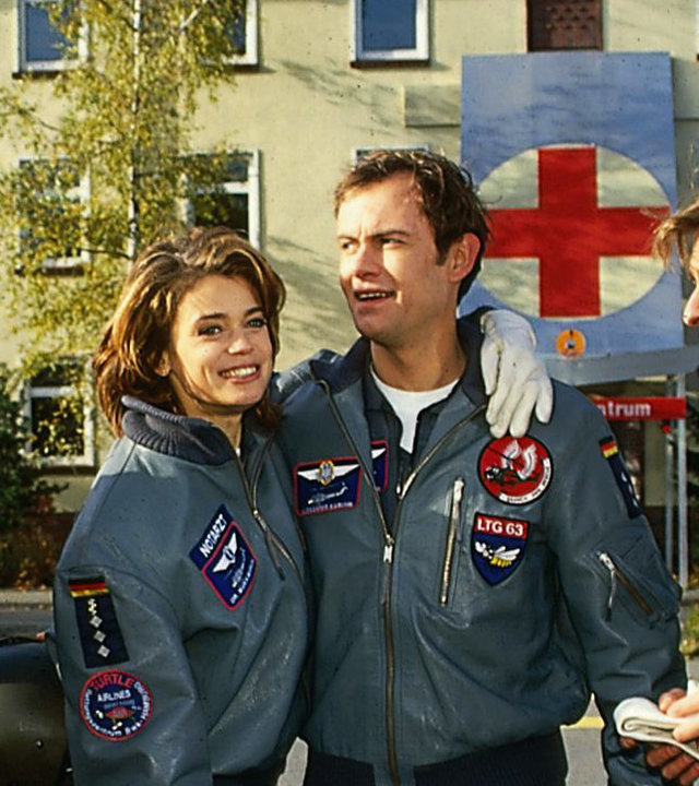 "Die Rettungsflieger - Sturzflug": Außenaufnahme - Die Rettungsflieger Max (Frank Stieren), Maren (Gerit Klink), Alex (Matthias Leja) und Leo (René Steinke) stehen auf einem Parkplatz lächelnd nebeneinander.