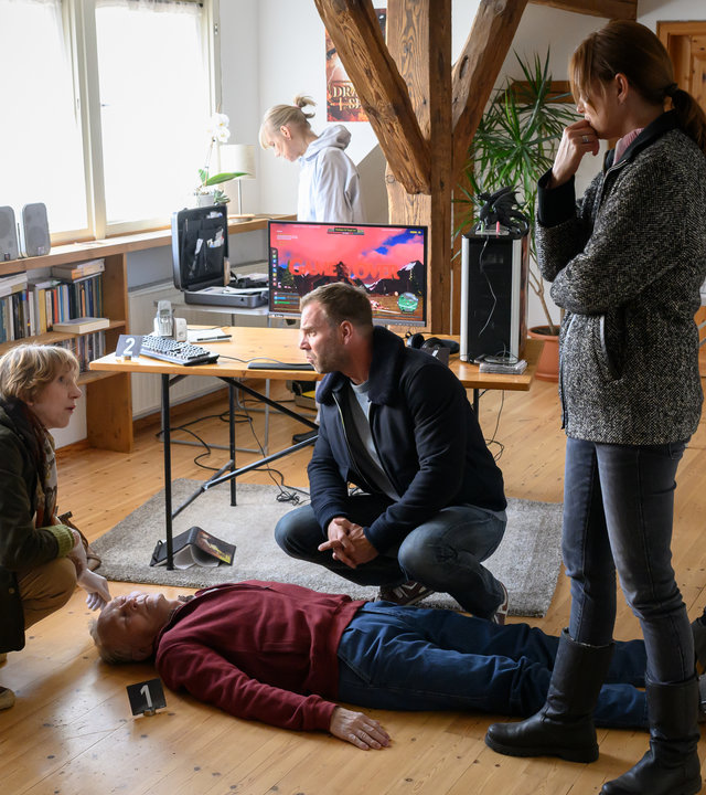 "SOKO Wismar - Game Over": Dr. Helene Sturbeck (Katharina Blaschke) kniet neben der leiche und klärt die Kommissarin Karoline Joost (Nike Fuhrmann) und Kommissar Lars Pöhlmann (Dominic Boeer) über die Todesursache von Reinhold Graf (Günter Petri) auf.