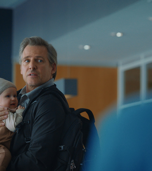 "Blutige Anfänger - Babyalarm": Im Büro der Moko. Torsten Kaiser (René Steinke) steht im Raum. Er hält ein Baby im Arm. Er blickt zu einer Person, die seitlich neben ihm steht.