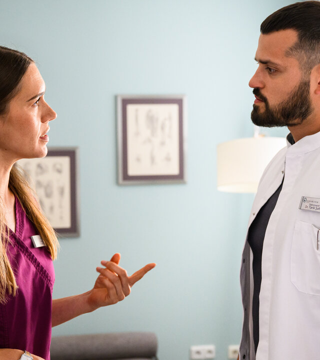 "Bettys Diagnose - Nichts als die Wahrheit": In einem Innenraum: Betty (Henrike Hahn) steht Tarik (Nicolas Fethi Türksever) gegenüber und zeigt dabei mit dem Finger auf ihn. Im Hintergrund hängen Bilder an der Wand.