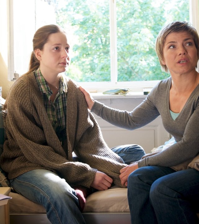 "SOKO Wismar - Ein Wolf kommt selten allein": Nina Konken (Alessandra Leandros) und Katrin Börensen (Claudia Schmutzler) sitzen auf Ninas Bett. Katrin hält die Hand von Nina und die andere legt sie beruhigend auf deren Schulter. Beide schauen zu jemandem, der nicht im Bild ist.