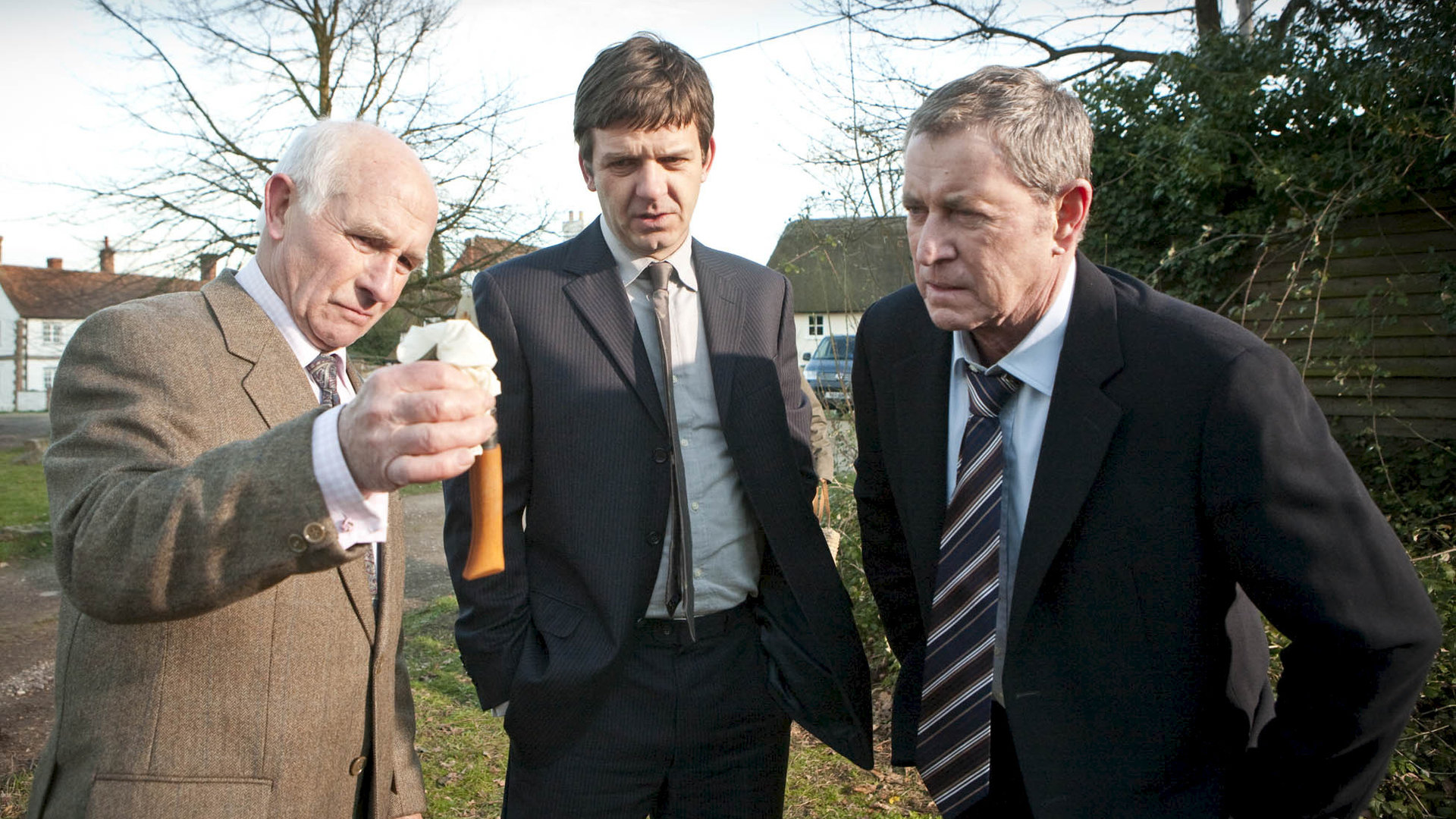 "Inspector Barnaby - Schreie in der Nacht": Außenaufnahme in einem Garten - Dr. George Bullard (Barry Jackson), DS Ben Jones (Jason Hughes) und DCI Tom Barnaby (John Nettles) begutachten eine Tatwaffe.