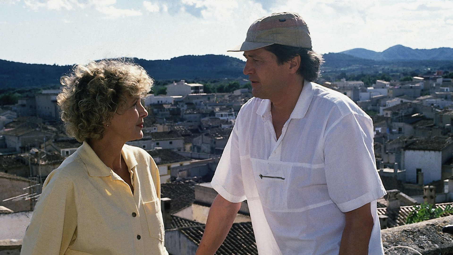 "Der Landarzt - Urlaub zu zweit": Dr. Mattiesen (Christian Quadflieg) und Annemarie (Gila von Weitershausen) stehen nebeneinander vor einem Geländer und schauen sich konzentriert an. Im Hintergrund ist ein mallorquinisches Dorf zu sehen.