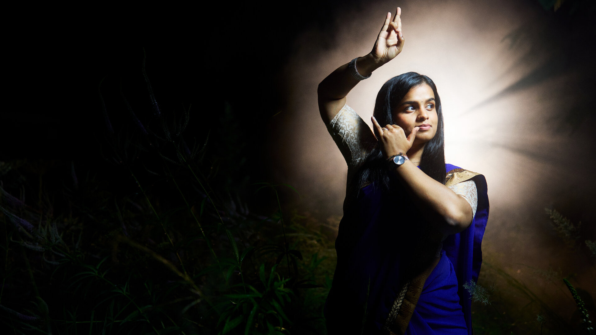 "37°Leben: Against all Gods: Shalom, Namasté, Peace out": Sagitha macht eine Geste ihres traditionellen tamilischen Tanzes. Sie trägt einen traditionellen Sari.
