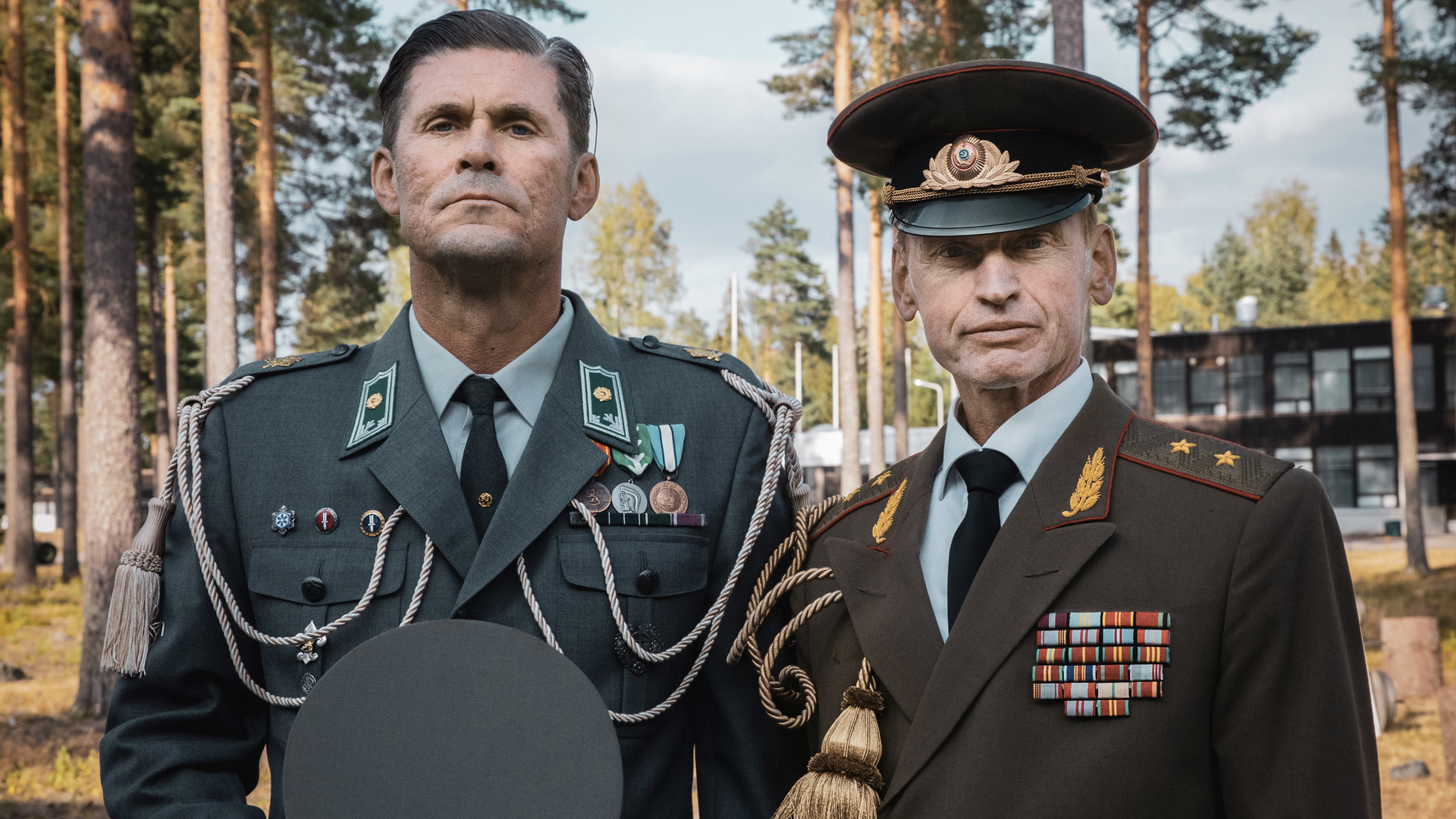 "Californian Commando - Die Überraschung": Major Miettinen (Tommi Korpela) und Major Poljakov (Andrei Tsumak) stehen in Paradeuniform aufrecht nebeneinander und schauen fokussiert geradeaus.
