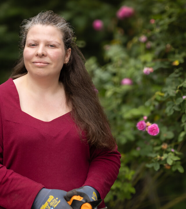 "einfach Mensch - Elisa Carow: Mein Gehirn tickt anders! (1)": Elisa Carow steht im Freien vor einem Rosenstrauch und blickt in die Kamera.