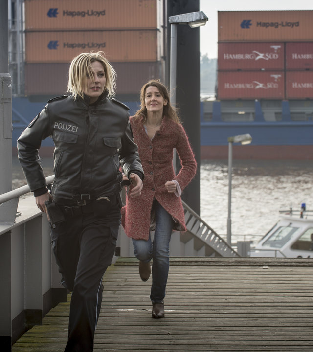 "Notruf Hafenkante - Gelegenheit macht Diebe": Melanie (Sanna Englund) und die Mutter des verschwundenen Kindes (Ursula Doll) rennen an einem Pier entlang. Im Hintergrund fährt ein Containerschiff.