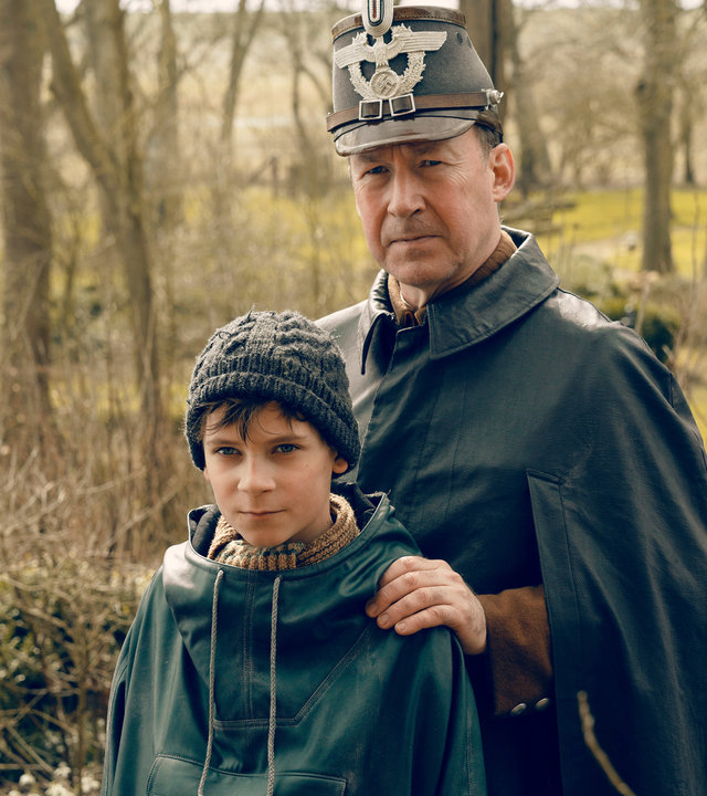 "Deutschstunde": Jens Ole Jepsen (Ulrich Noethen) und Siggi Jepsen (Levi Eisenblätter) stehen nebeneinander und schauen in die Kamera. Jens Ole hat seine Hände auf die Schultern seines Sohnes gelegt.