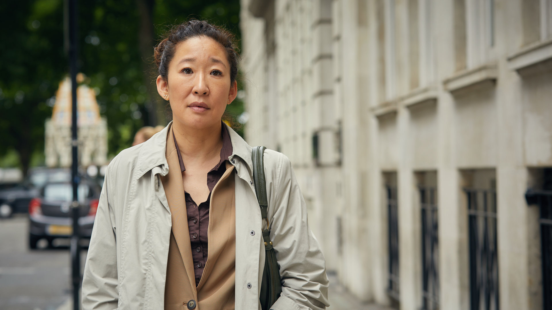 "Killing Eve – Nettes Gesicht": Eve Polastri (Sandra Oh) steht in einem Trenchcoat auf der Straße und schaut nachdenklich in die Ferne.