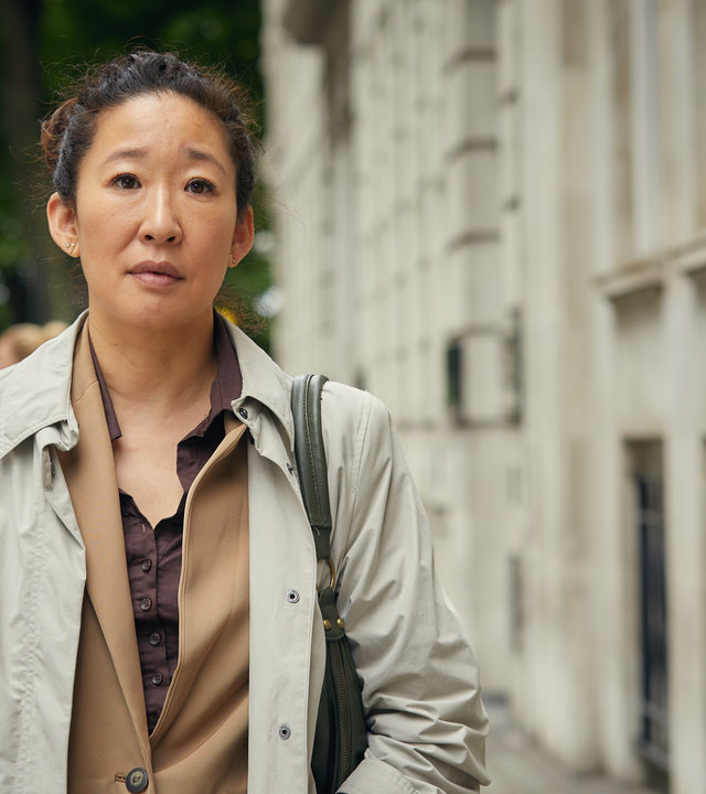 "Killing Eve – Nettes Gesicht": Eve Polastri (Sandra Oh) steht in einem Trenchcoat auf der Straße und schaut nachdenklich in die Ferne.