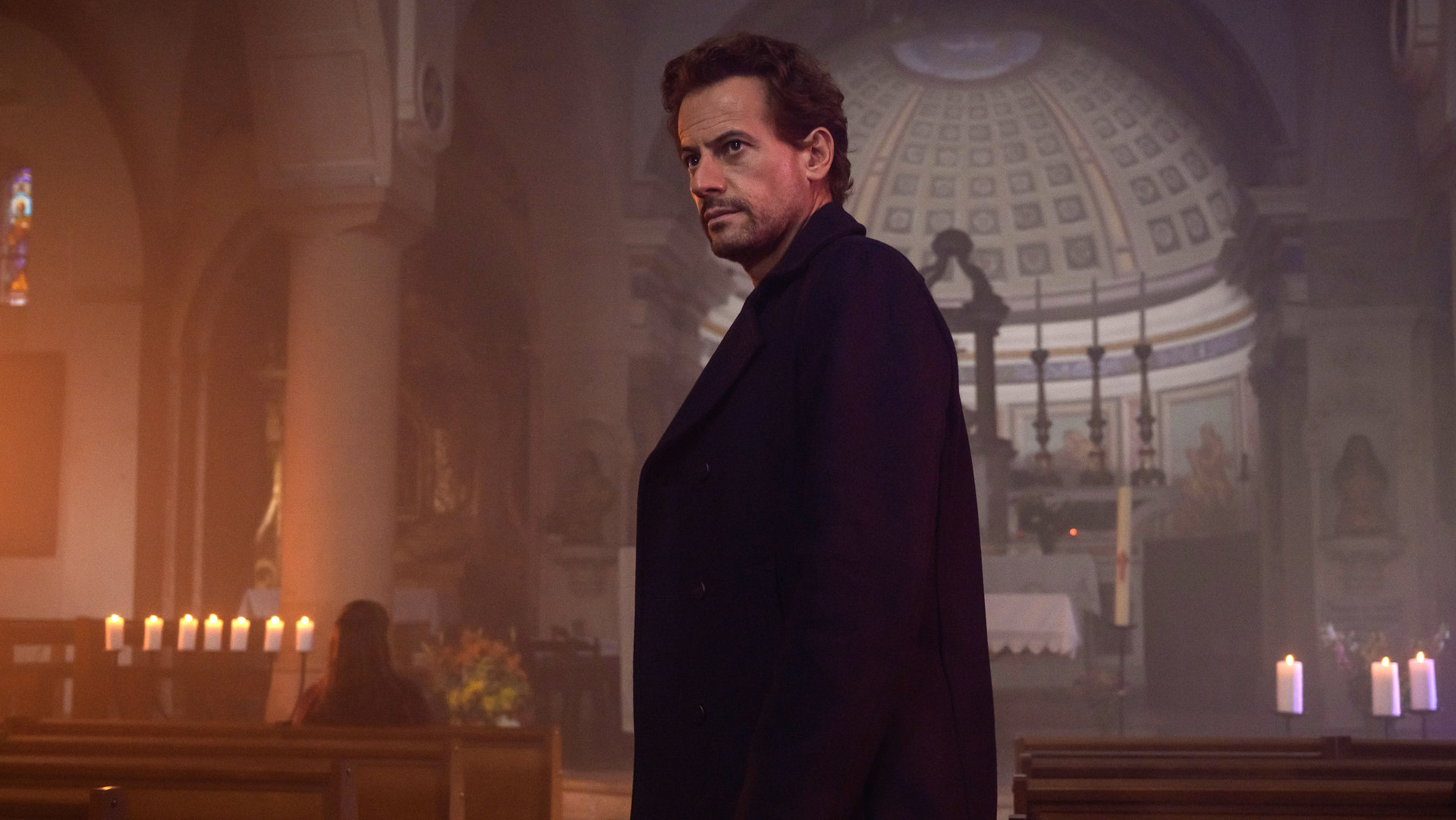 "Das Mädchen und die Nacht (5)": Thomas (Ioan Gruffudd) steht im Mittelgang einer Kirche. Er ist dunkel gekleidet. Im Hintergrund sitzt Fanny (Vahina Giocante) in einer der Kirchenbänke und wartet auf ihn.