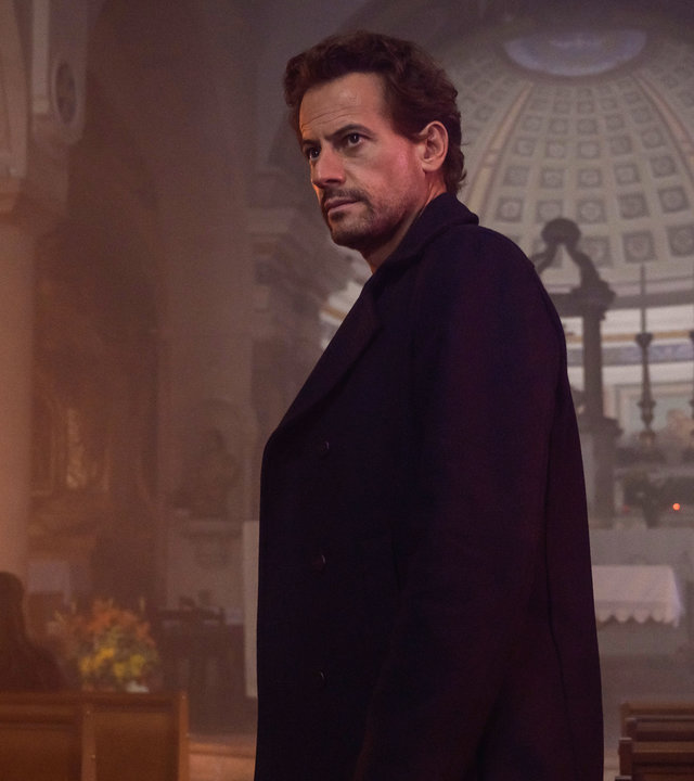 "Das Mädchen und die Nacht (5)": Thomas (Ioan Gruffudd) steht im Mittelgang einer Kirche. Er ist dunkel gekleidet. Im Hintergrund sitzt Fanny (Vahina Giocante) in einer der Kirchenbänke und wartet auf ihn.