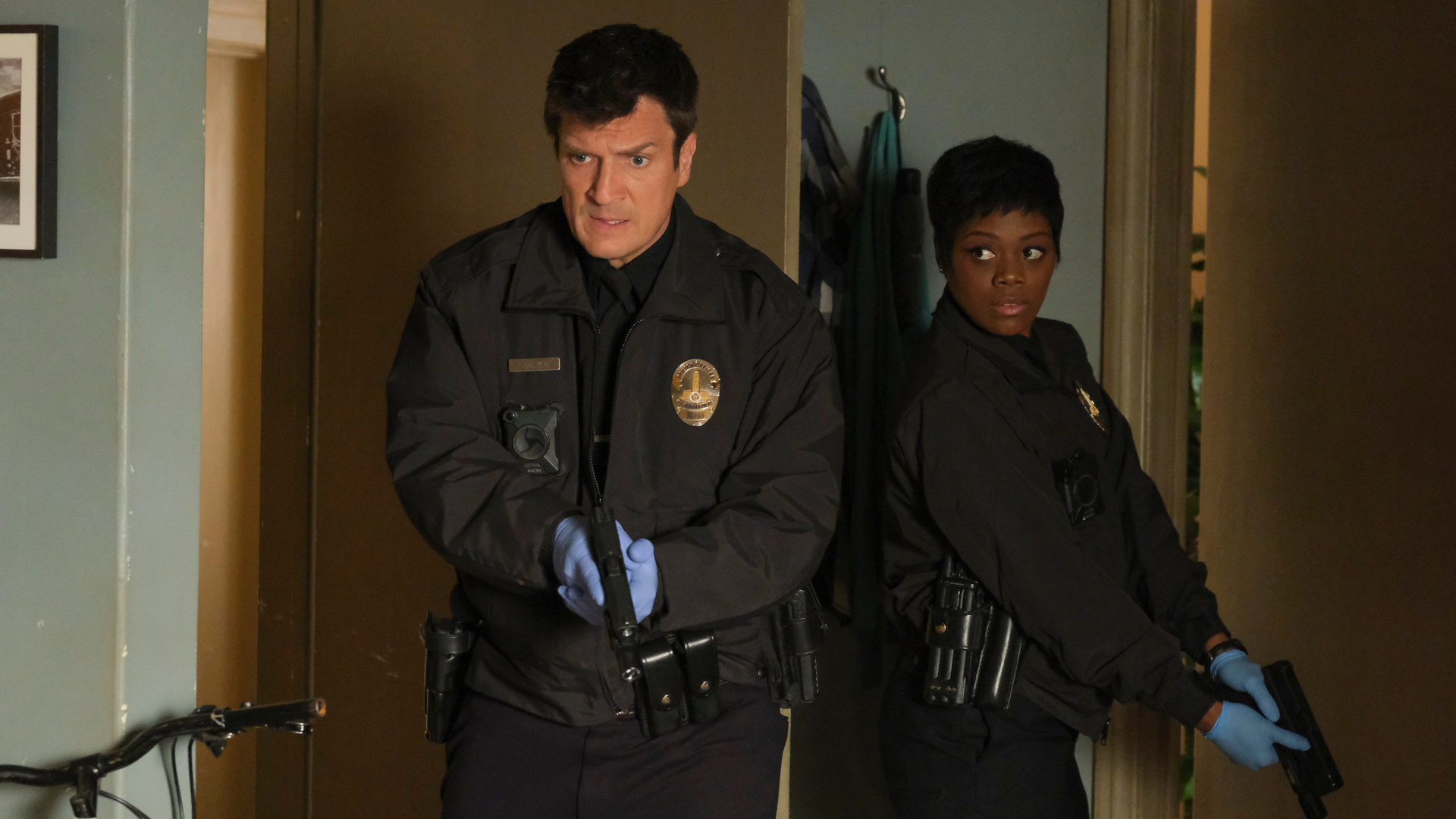 "The Rookie - Freier Fall": John Nolan (Nathan Fillion) und Talia Bishop (Afton Williamson) stehen in der Eingangstür einer Wohnung und haben ihre Pistole in den Händen.