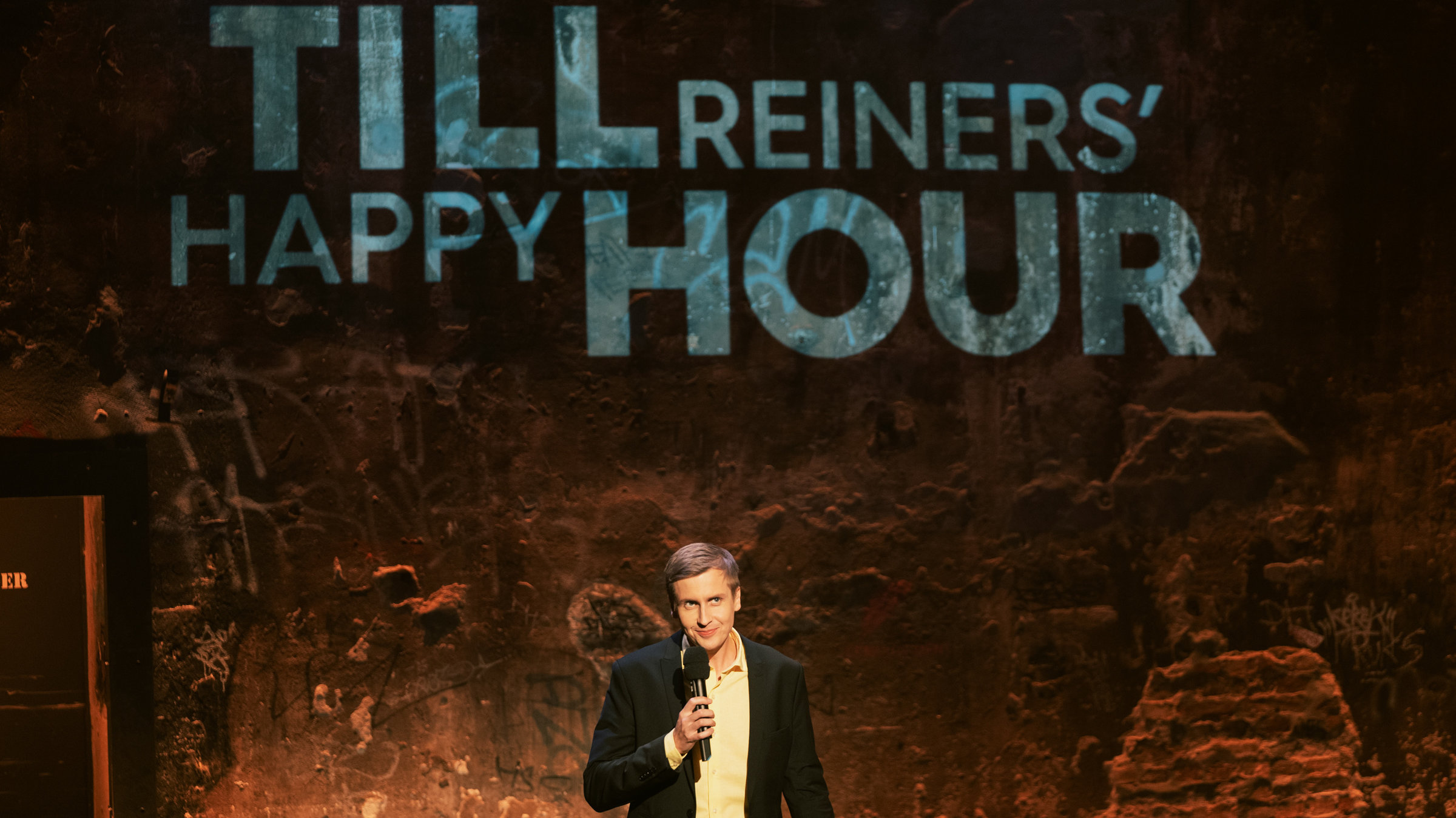"Till Reiners´ Happy Hour": der Gastgeber Till Reiners steht auf der Bühne und unterhält sein Publikum.