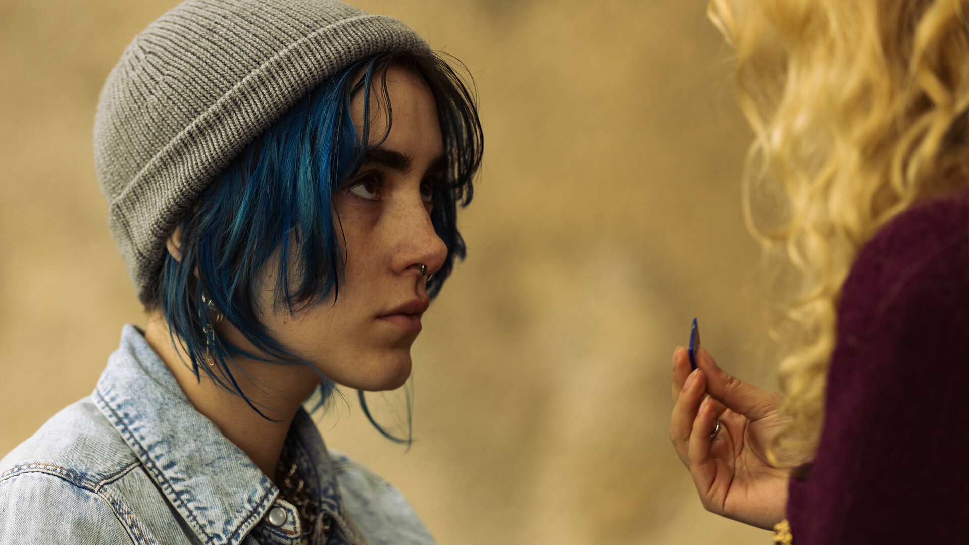 "Phoenix - Change Or Die: Alles brennt": Nina (Alva Schäfer) blickt zu Lyne (Pauline Pollmann), die nur im Anschnitt zu sehen ist. Diese hält Nina eine SD-Karte hinhält.