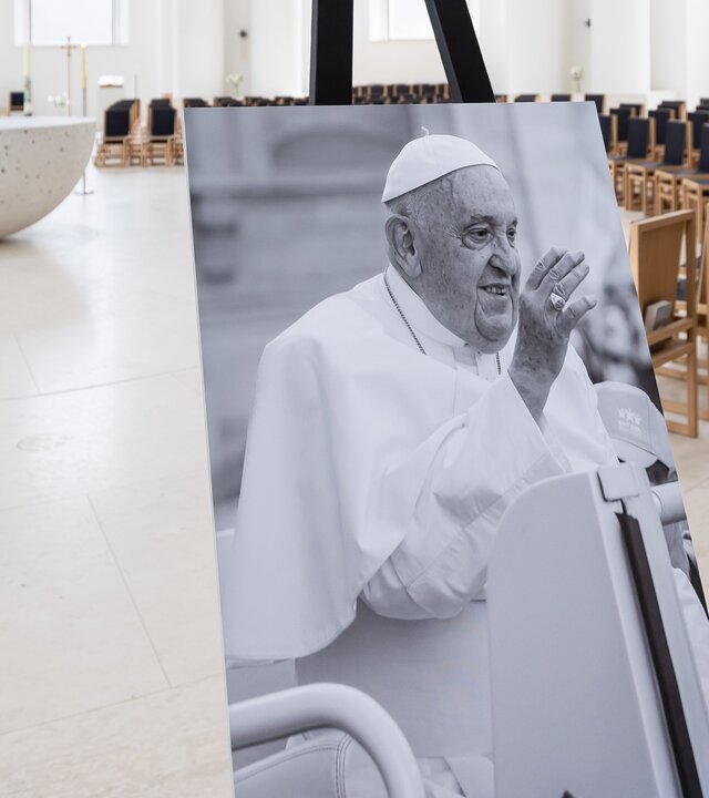 "Requiem für Papst Franziskus": In der Sankt Hedwigs-Kathedrale zu Berlin steht ein Schwarz-Weiß-Foto des verstorbenen Papstes auf einer Staffelei, umgeben von schlichter, sakraler Atmosphäre.