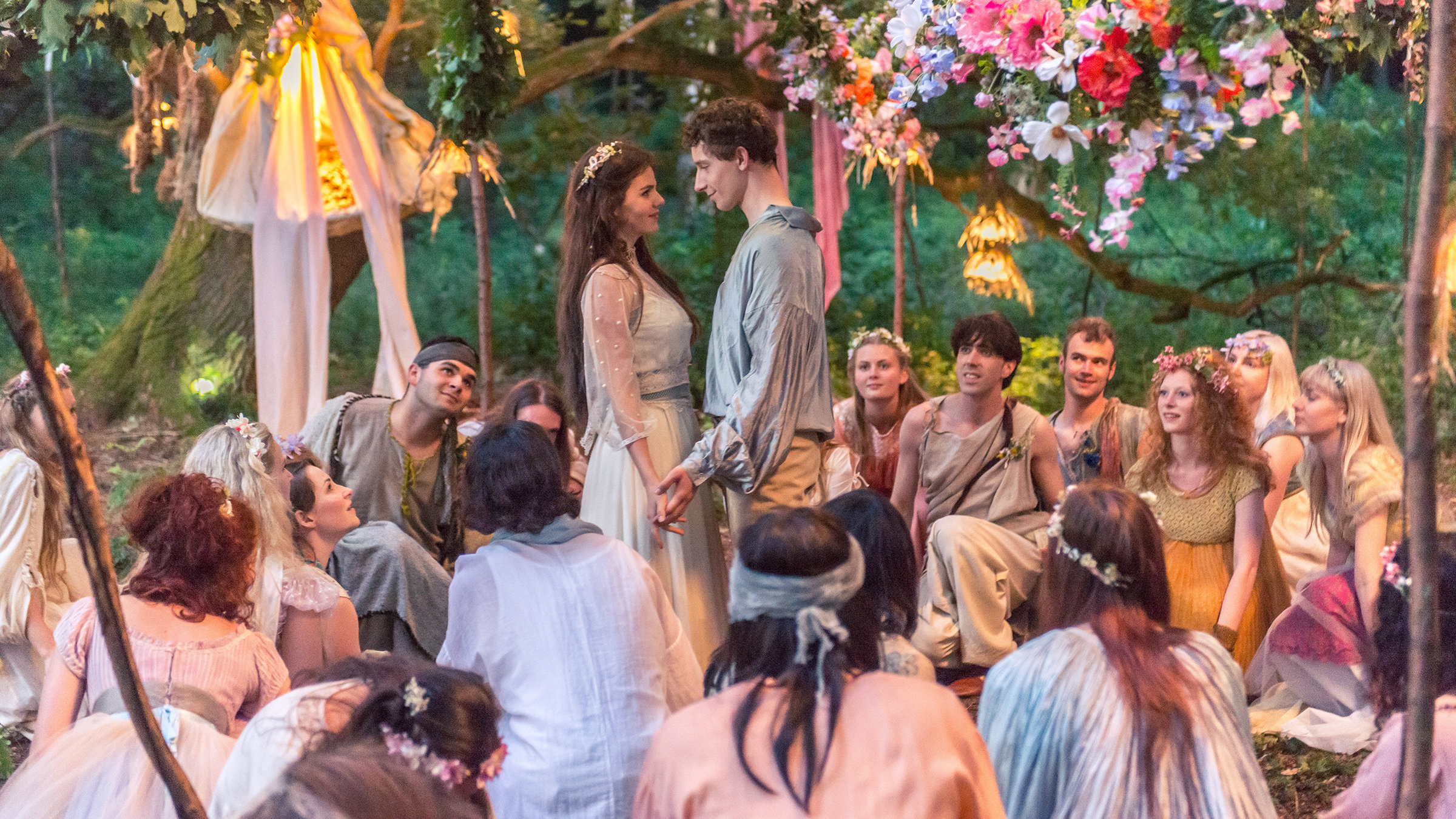 "Prinz Himmelblau und Fee Lupine": Fee Lupine (Ruby O. Fee) und Prinz Himmelblau (Jonathan Berlin) umringt von in der Hocke sitzenden Menschen.