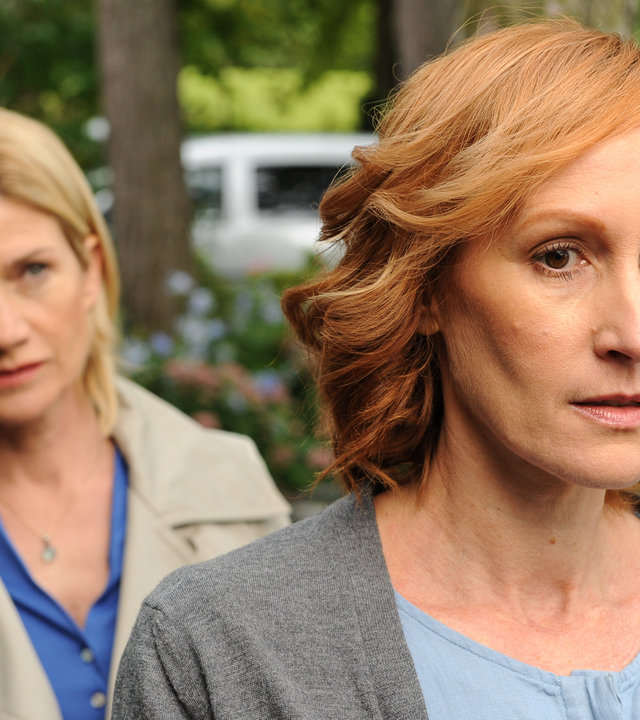 "SOKO Stuttgart - Seitenwechsel": Martina Seiffert (Astrid M. Fünderich) steht hinter Marlene Hahn (Nicole Beutler) und beobachtet sie genau. Sie befinden sich im Garten. Im Hintergrund ist unscharf ein weißer Lieferwagen zu sehen.