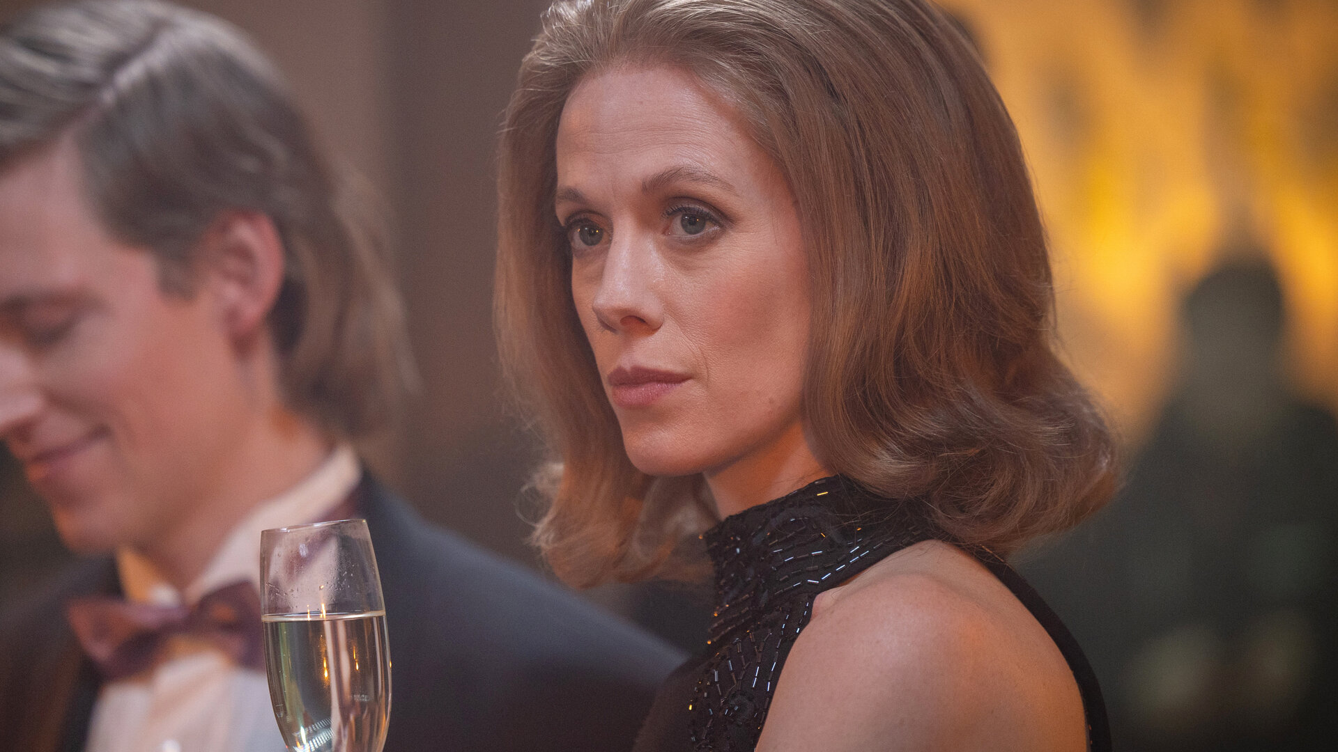 "Stenbeck - TV3 - Die Revolution aus London": In einem schwarzen Abendkleid und mit einem Sektglas in der Hand, blickt Merrill (Zoe Boyle) melancholisch in die Ferne.