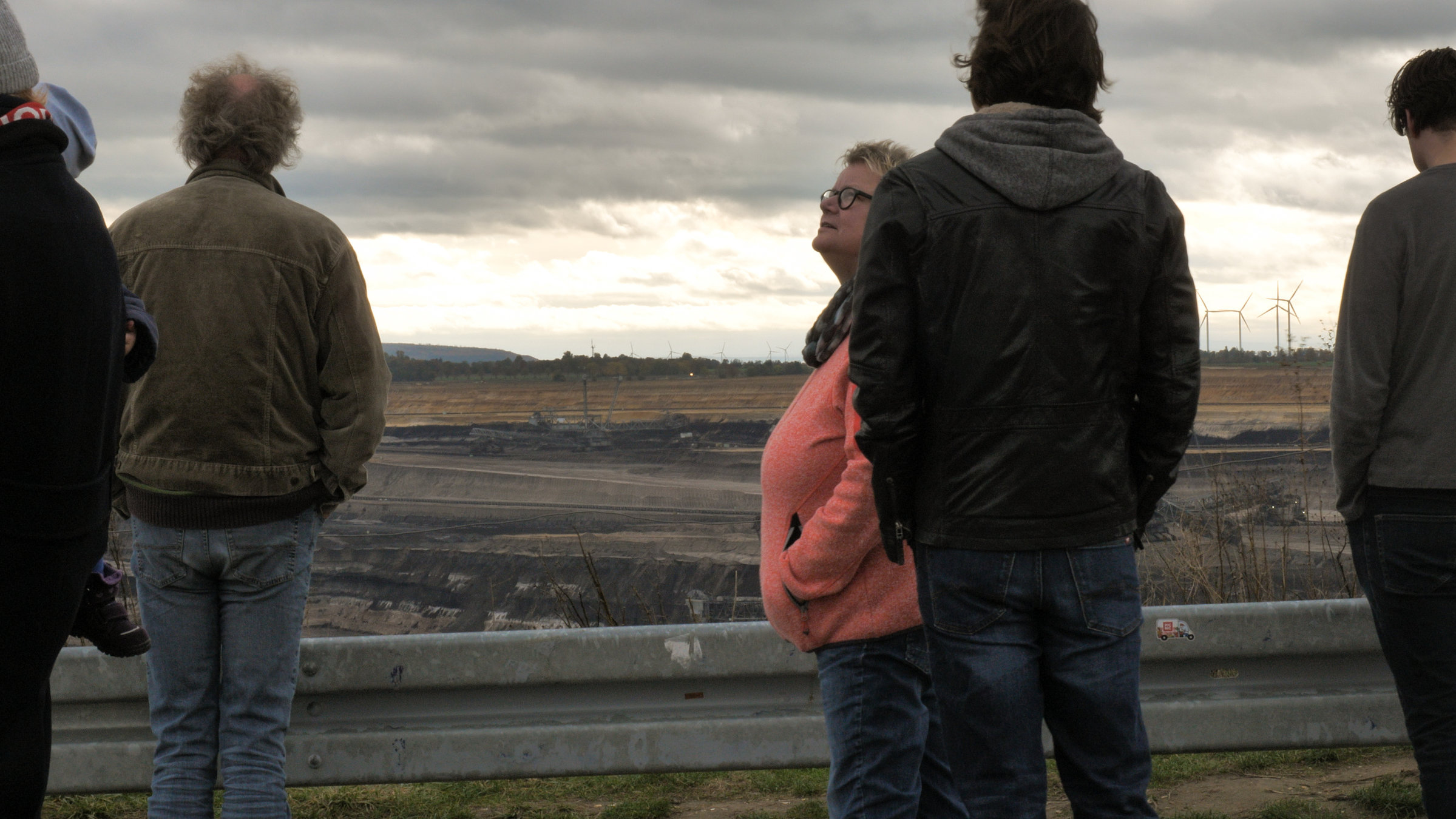 "Lamarck": Vier Personen stehen mit dem Rücken zur Kamera und blicken auf einen Braunkohle-Tagebau. Eine Person blickt seitlich in den Himmel.