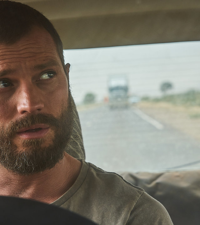 "The Tourist - Duell im Outback: Im Tau von Lethes Flut": Der Fremde (Jamie Dornan) sitzt am Steuer eines Wagens und beobachtet einen Truck im Rückspiegel.