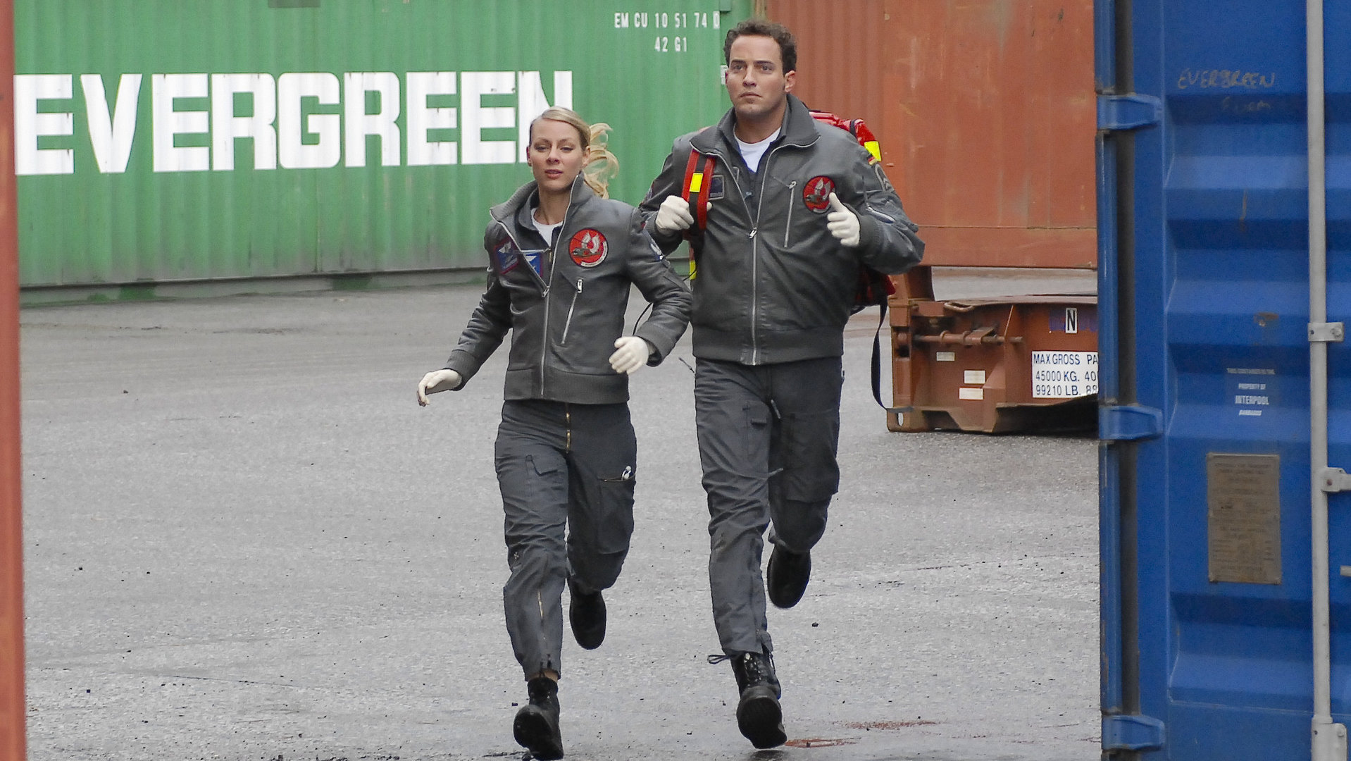 "Die Rettungsflieger - Schöne Aussichten": Sabine (Marlene Marlow)  und Jonny (Patrick Wolff) rennen mit der Notfallausrüstung durch den Containerhafen.