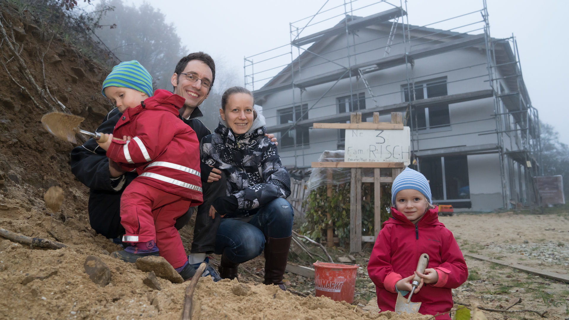 "37 °: Wagnis Hausbau": Vater Mirko und Mutter Marina mit zwei kleinen Kindern, links Fabian und rechts Elena, spielen im Sand vor einem Rohbau.