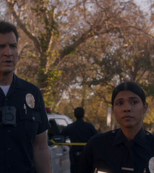 "The Rookie - Todesurteil": Officer John Nolan (Nathan Fillion) und Officer Celina Juarez (Lisseth Chavez) stehen auf einer abgesperrten Straße, umgeben von Polizeifahrzeugen. Ihre Blicke sind ernst und richten sich in die gleiche Richtung.