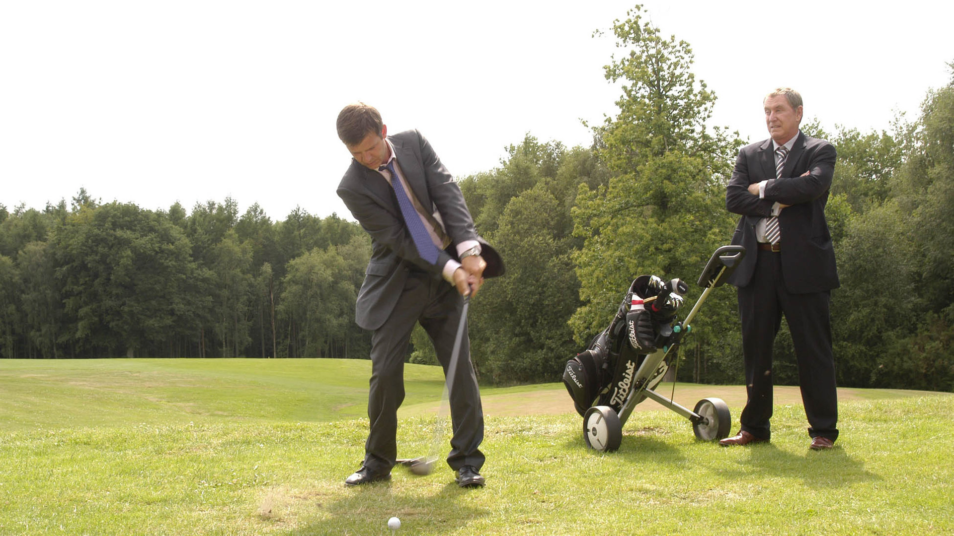 "Inspector Barnaby - Mord - Nur für Mitglieder": DS Ben Jones (Jason Hughes) beim Abschlag auf dem Golfplatz. DCI Tom Barnaby (John Nettles) steht daneben, vor ihm steht ein Golfbag.