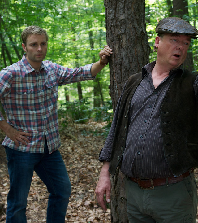 "SOKO Wismar - Fotofalle": Katrin Börensen (Claudia Schmutzler) und Nils Theede (Jonas Laux) stehen im Wald mit dem Jagdpächter Hansjörg Strack (Peter Kurth), der mir einer Hand auf etwas weiter vorne zeigt.