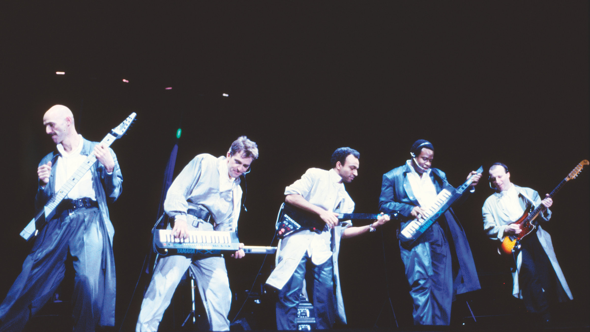 "Peter Gabriel: Live in Athens": Peter Gabriel und vier weitere Musiker stehen mit ihren Instrumenten auf einer Bühne und geben ein Konzert.