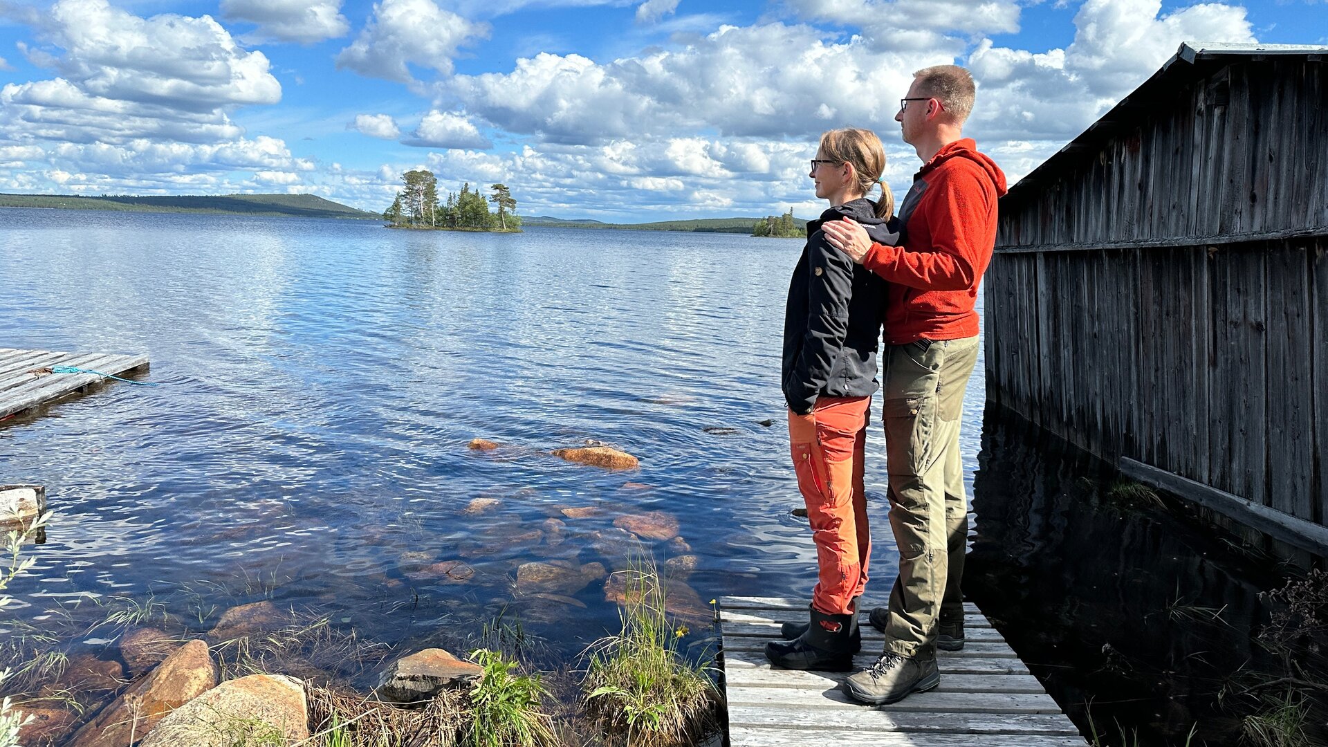 "Abenteuer Auswandern - Neuanfang in Schweden": Andrea Windolph und Alexander Blumenau stehen auf einem Steg am Wasser und schauen seitlich in die Ferne. Die Sonne scheint, am Himmel ziehen Wolken vorbei.