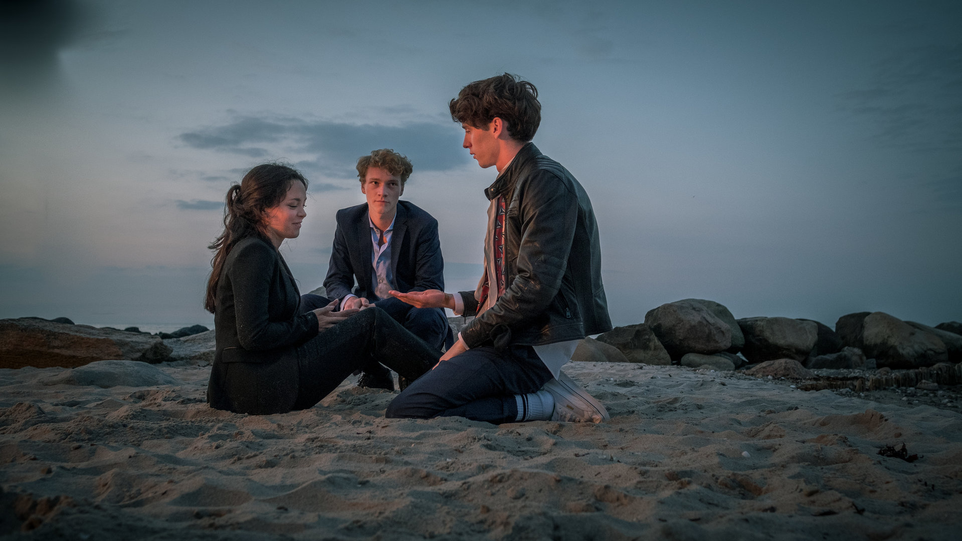 "Das Mädchen am Strand (2)": Jule Reinhardt (Tijan Marei), Jakob Bruns (Bruno Alexander), David Jung (Oskar Belton) sitzen zusammen am Strand.