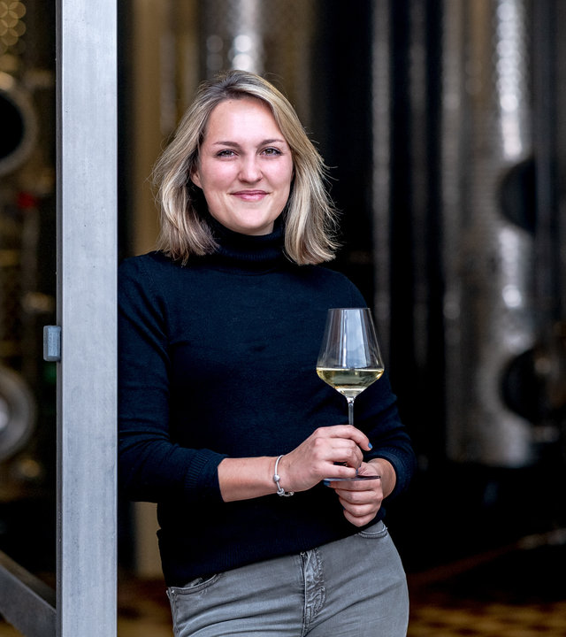 "37°Leben - In Papas Fußstapfen": Sophie Egert mit Weinglas vor der Kelterhalle des väterlichen Winzerbetriebs.