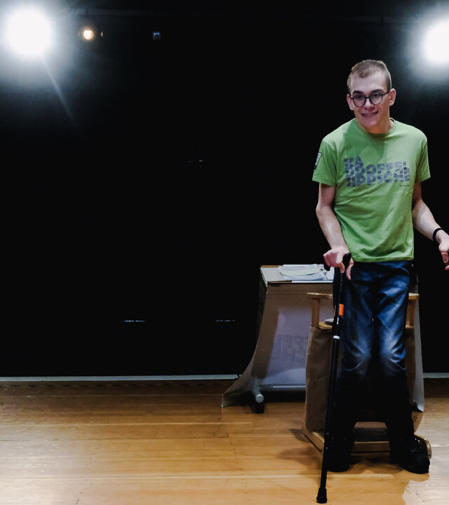 "einfach Mensch, Folge: Luis Adam: Lacht ruhig über mich!": Kabarettist Luis Adam steht unterstützt von zwei Krücken auf der Bühne.