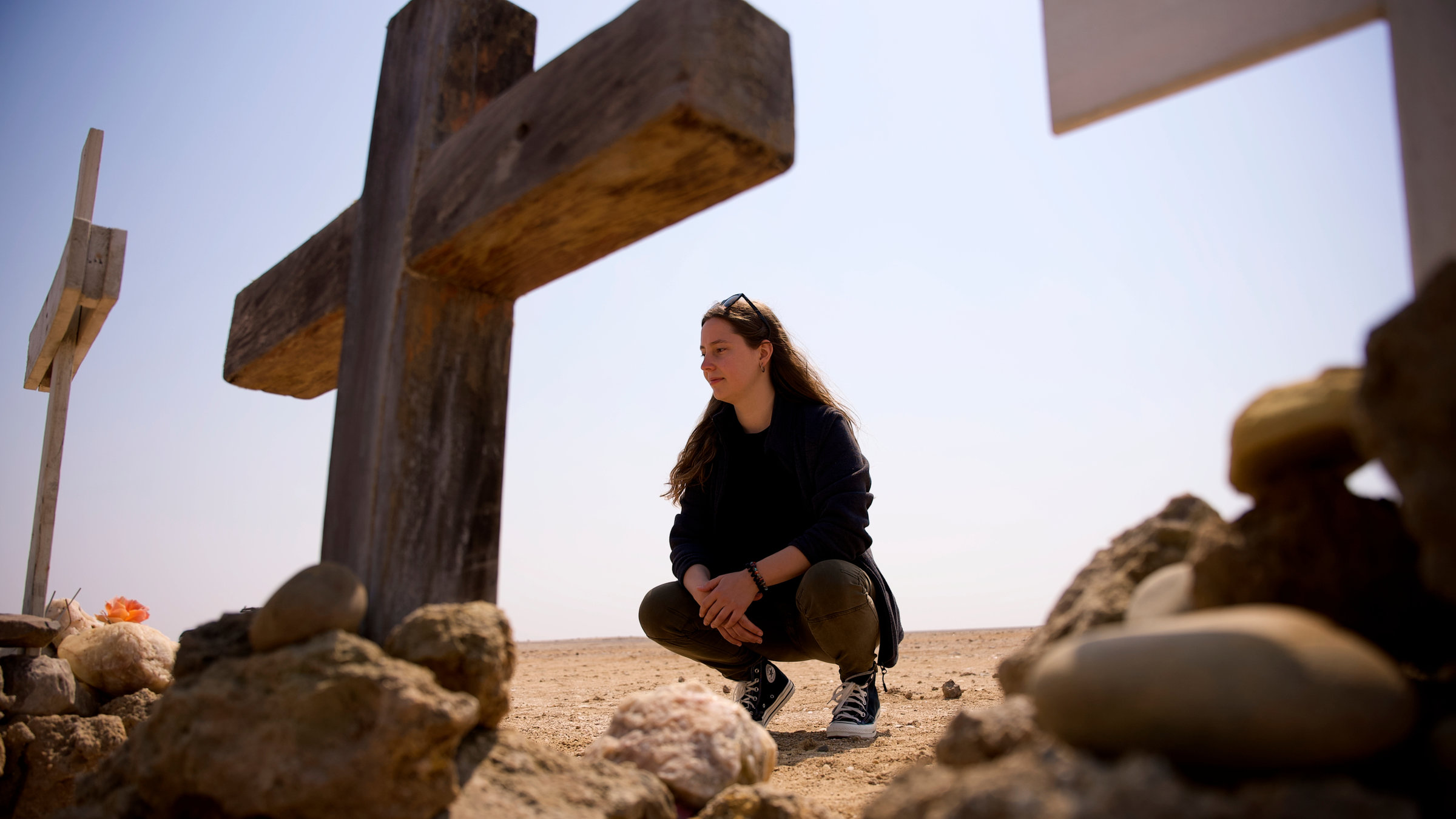 "37°: Totgerast - Wie Angehörige weiterleben": Antonia Joschkos hockt vor einem Kreuz in der Namibischen Wüste und schaut dieses an. Ein weiteres Kreuz steht mittig im Vordergrund, am rechten Bildrand ist ein weiteres Kreuz im Anschnitt zu sehen.