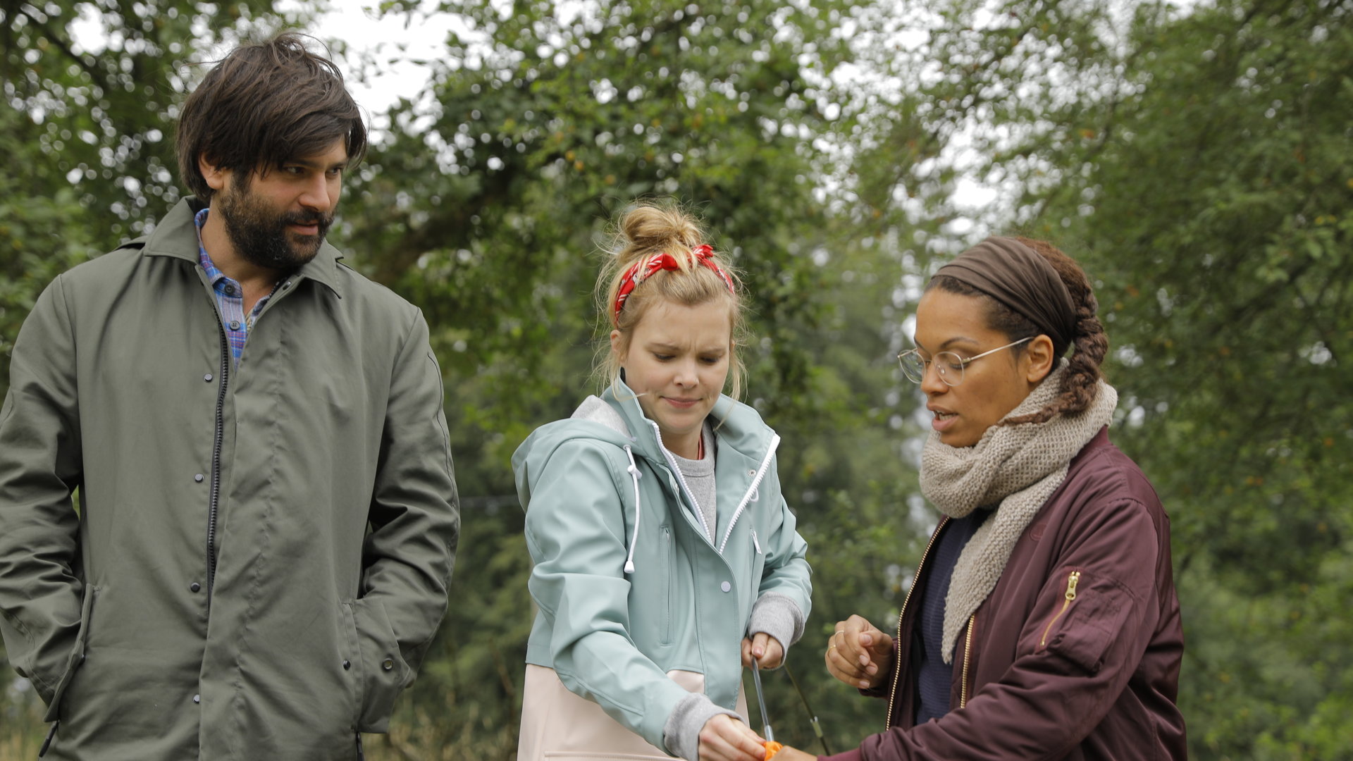 “Andere Eltern - Episode 6“: Paula (Maike Jüttendonk) und Yaa (Rebecca Lina) bauen ein Zelt auf, während sich Jannos (Jasin Challah) mit ihnen unterhält.