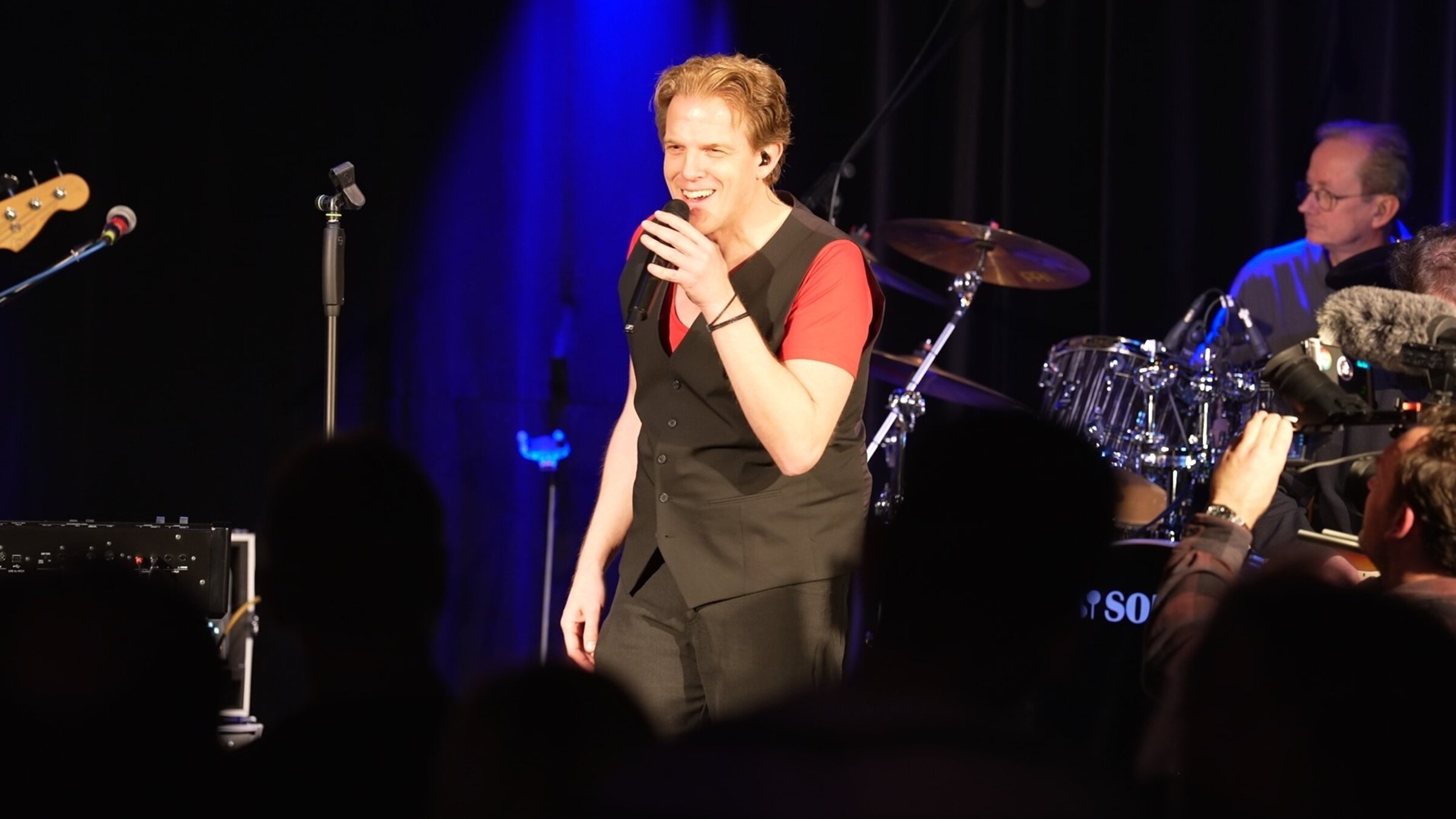 "ZDF.reportage: Der schwere Weg zum Traumjob": Karl Frenzel auf der Bühne mit einem Mikrofon in der Hand.