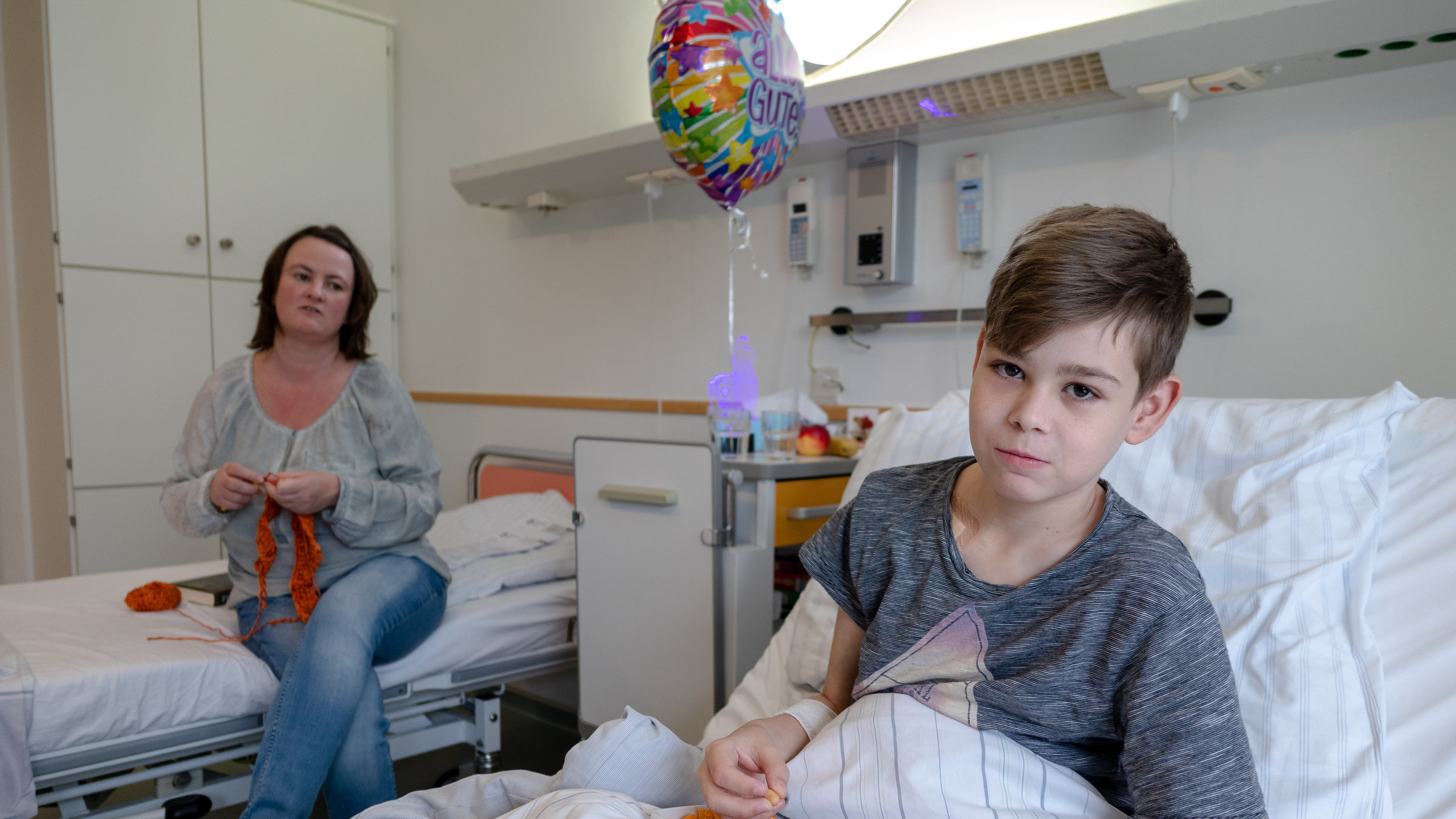 "37°: Ich gebe dir meine Niere - Rettung durch eine Lebendspende": Adrian liegt in einem Krankenhaus-Bett, hinter ihm sitzt seine Mutter Nicole.