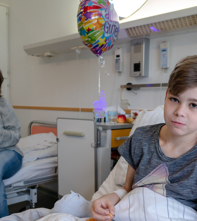 "37°: Ich gebe dir meine Niere - Rettung durch eine Lebendspende": Adrian liegt in einem Krankenhaus-Bett, hinter ihm sitzt seine Mutter Nicole.