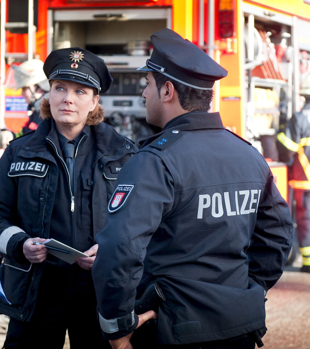 "Notruf Hafenkante - Alles Einstein": Claudia (Janette Rauch) und Tarik (Serhat Cokgezen) unterhalten sich mit Heiner Bartels (Robert Schupp) auf der Straße. Im Hintergrund steht ein Feuerwehrauto.