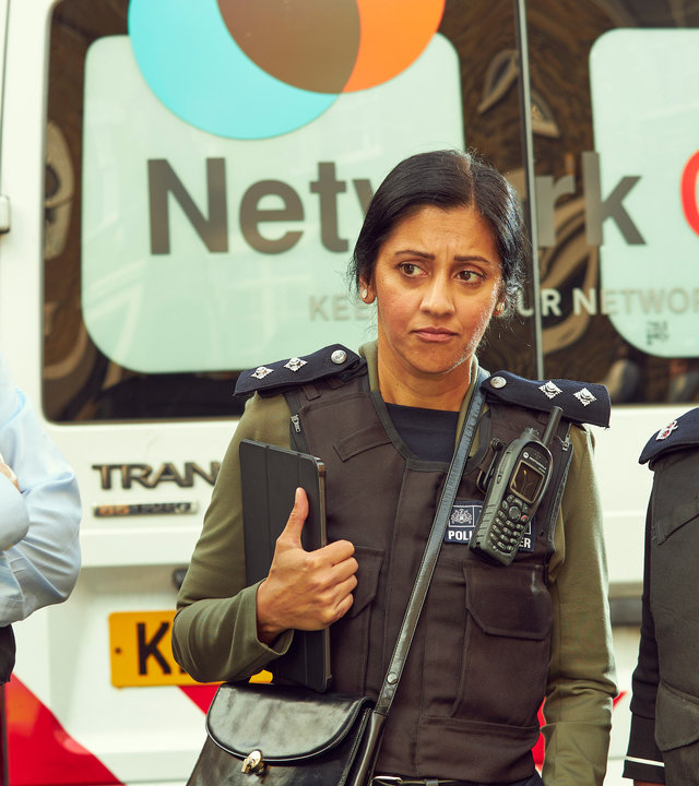 "Trigger Point: Endspiel": Thom (Mark Stanley), Desai (Manjinder Virk) und Einsatzleiterin Hamilton (Nadine Marshall) stehen mit Schutzwesten hinter einem Lieferwagen zusammen. Thom hat die Arme vor sich verschränkt und schaut die beiden Frauen an.