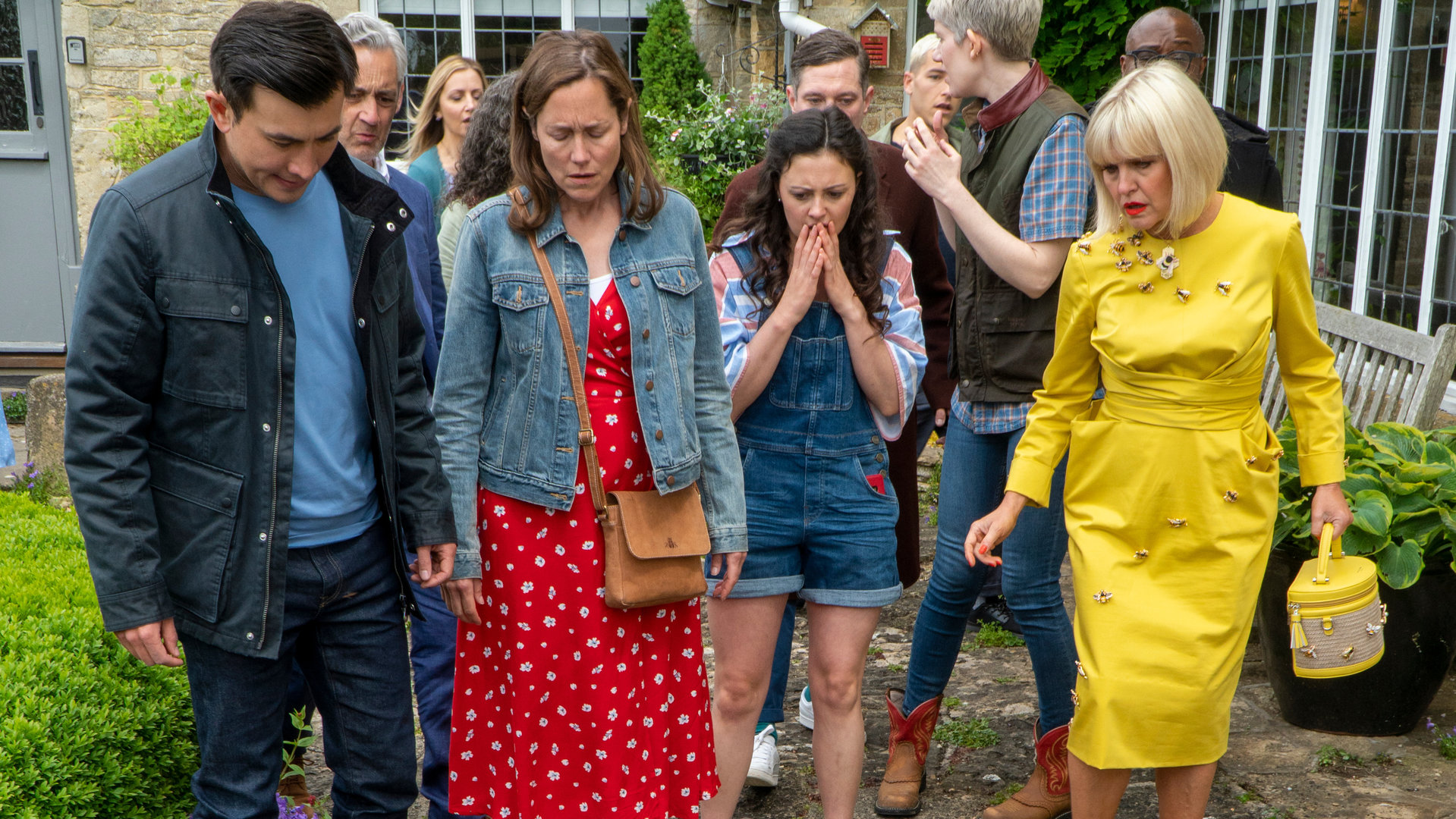 "Agatha Raisin - Und das tödliche Kirchenfest Teil 2": Agatha (Ashley Jensen), Toni (Jodie Tyack), Sarah (Lucy Liemann) und D.S. Bill Wong (Matt McCooey) stehen vor einer Menschenmenge und schauen erschüttert auf den Boden.