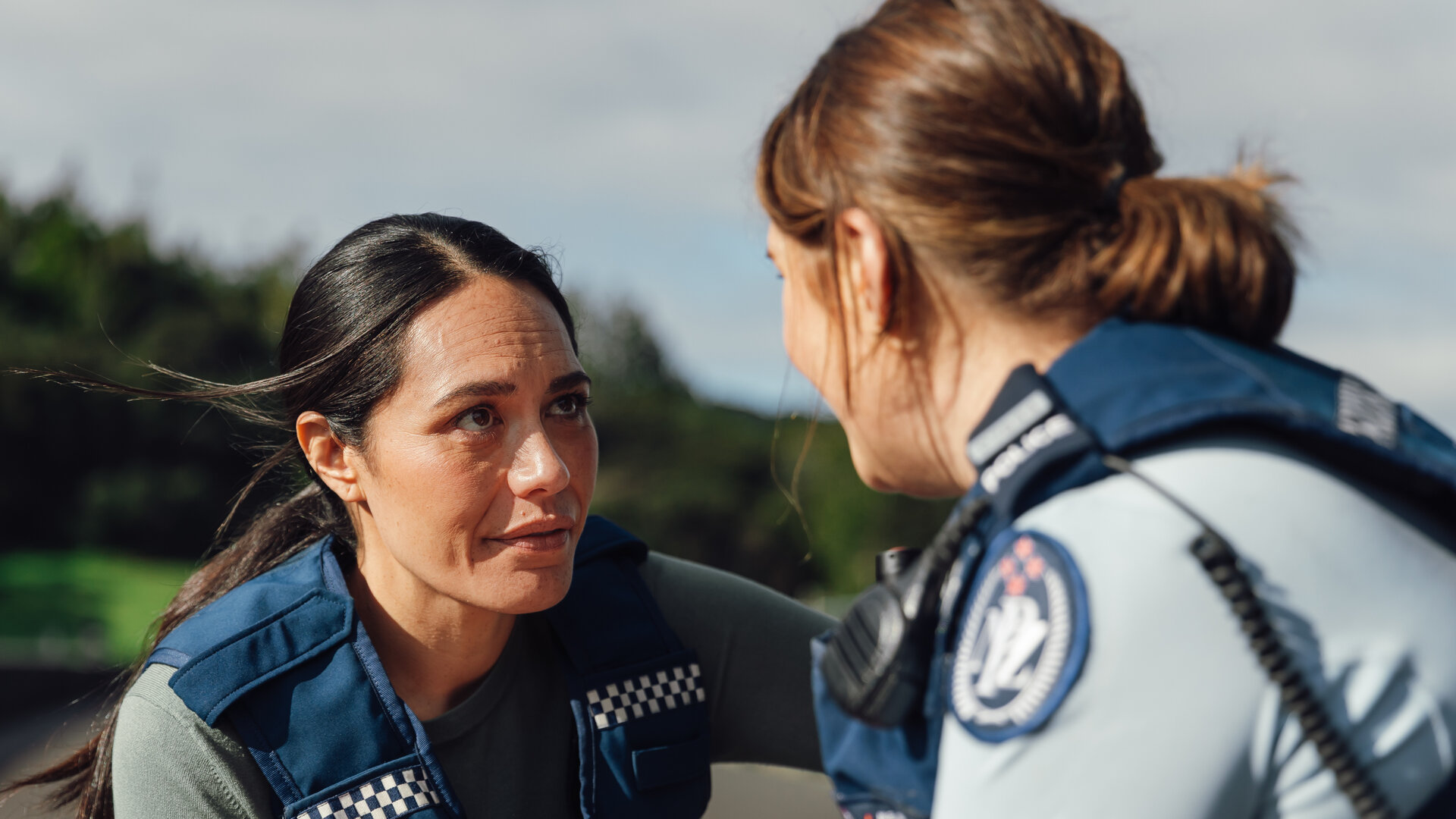 "Back Up - Auf Streife mit der Ex: Ein Hai in Geldnot": Detective Mihi Renata (Roimata Fox) und Police Constable Deb Brighton (Morgana O'Reilly) tragen Polizeiuniform, stehen im Freien und schauen sich an.