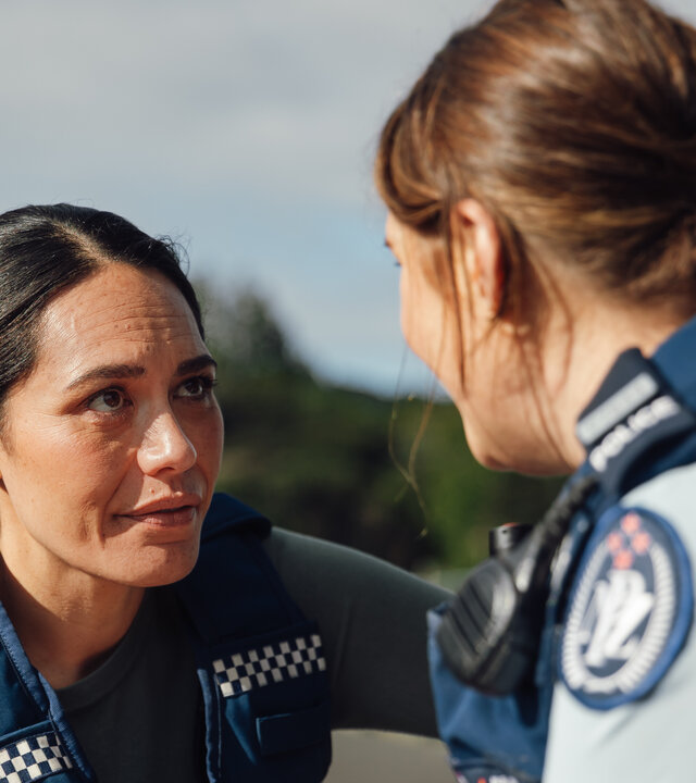 "Back Up - Auf Streife mit der Ex: Ein Hai in Geldnot": Detective Mihi Renata (Roimata Fox) und Police Constable Deb Brighton (Morgana O'Reilly) tragen Polizeiuniform, stehen im Freien und schauen sich an.