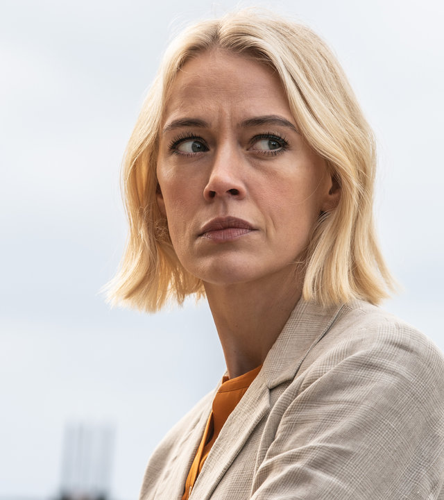 "The Mallorca Files - Einmal ein Held sein": Miranda (Elen Rhys) steht an einem bewölkten Tag draußen. Sie trägt einen beigefarbenen Blazer.