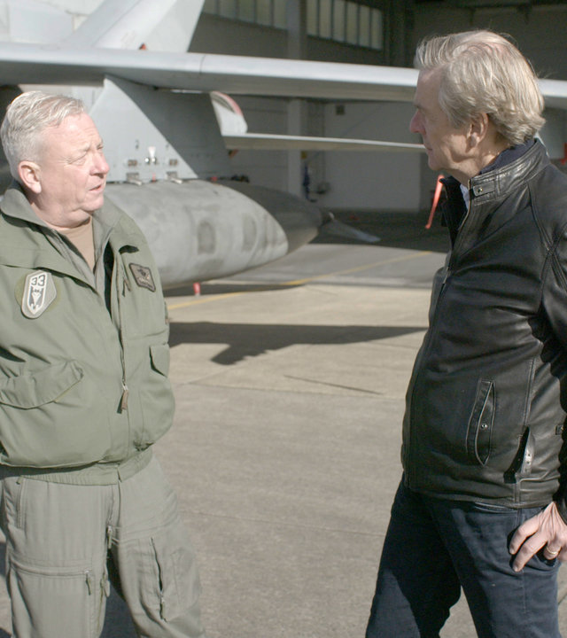 "ZDFzeit: Putins Tabubruch - die neue Angst vor der Bombe": Oberst Thomas Schneider und Claus Kleber stehen vor einem Kampfflugzeug und unterhalten sich.