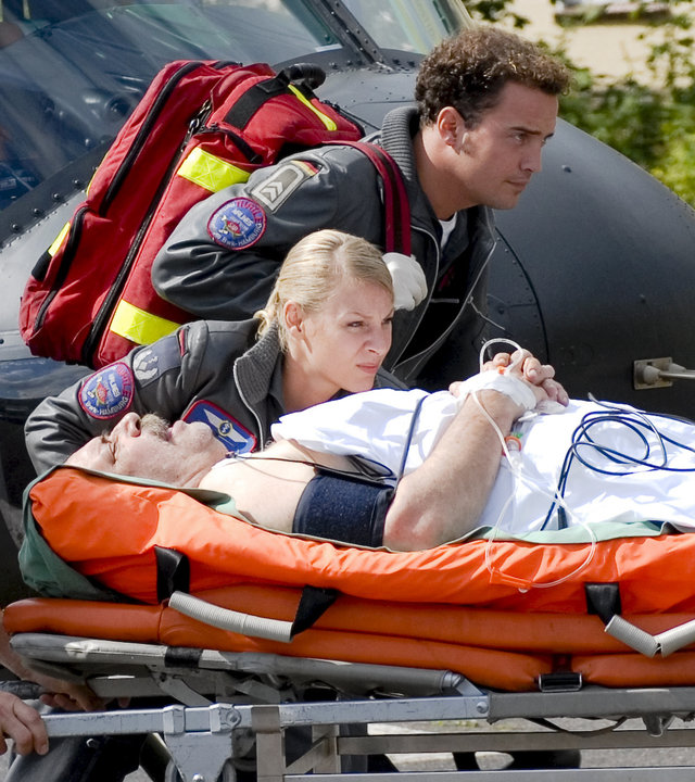 "Die Rettungsflieger - Muttersorgen": Dr. Sabine Petersen (Marlene Marlow) und Johannes von Storkow (Patrick Wolf) neben einer Krankentrage mit dem verletzten Bauern Heinrich (Klaus Dittmann), die ein Pfleger vom Hubschrauber Richtung Krankenhaus schiebt.
